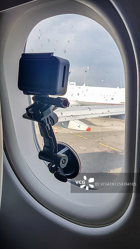 捕捉瞬间：手持相机固定在飞机舷窗上，拍摄度假旅程的延时摄影，留作纪念图片素材