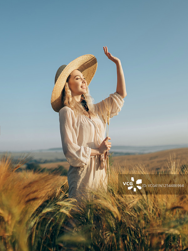 年轻漂亮的女人站在高高的草丛中图片素材