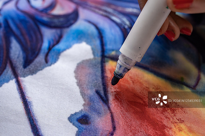 女艺术家用蓝色记号笔在T恤上绘画图片素材