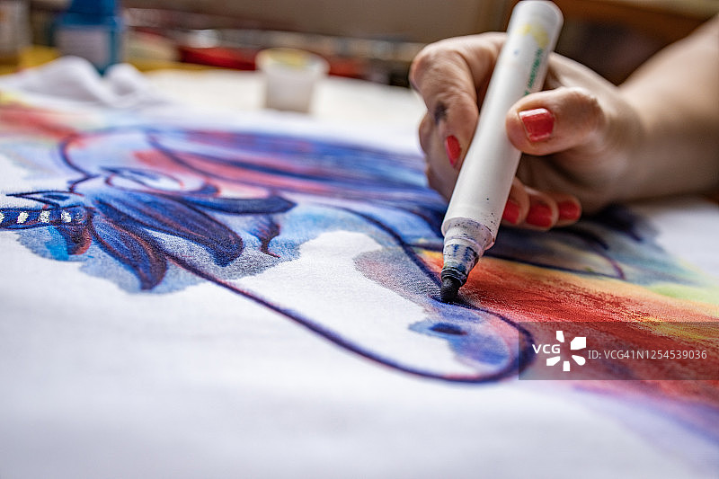 女艺术家用蓝色记号笔在T恤上绘画图片素材
