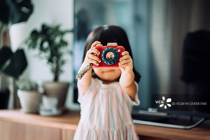 可爱亚洲女童在家用木制玩具相机拍照图片素材