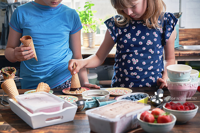 小女孩们准备带各种配料、水果和糖果的冰淇淋甜筒图片素材