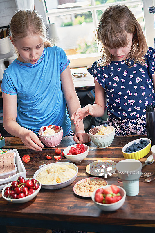 小女孩们准备带各种配料、水果和糖果的冰淇淋甜筒图片素材