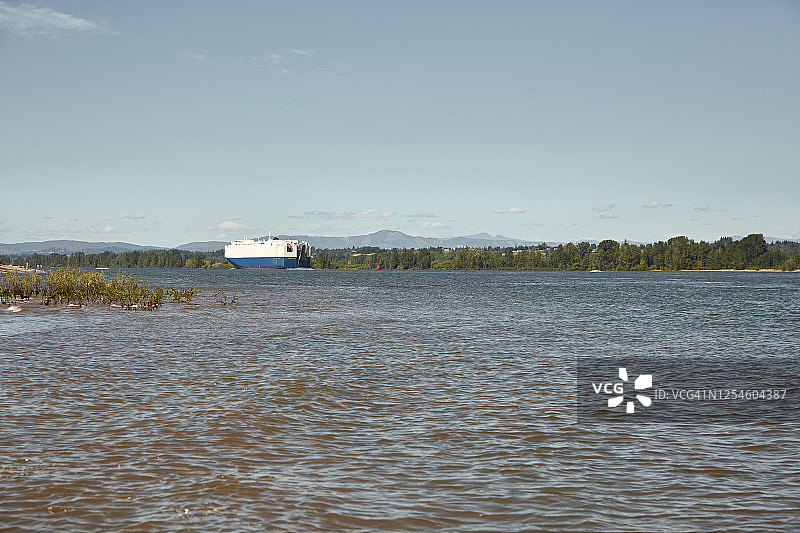 从索维岛看哥伦比亚河上行驶的大型运输车，背景是圣海伦斯山图片素材