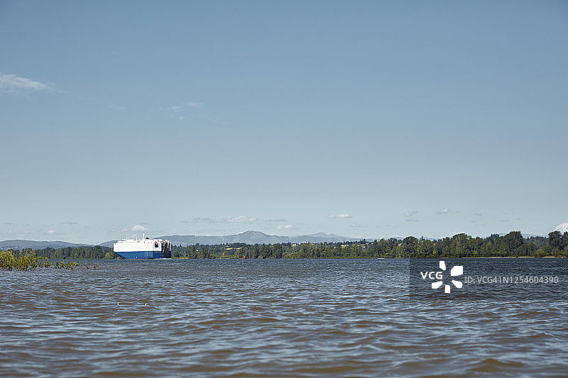 从索维岛看哥伦比亚河上行驶的大型运输车，背景是圣海伦斯山图片素材
