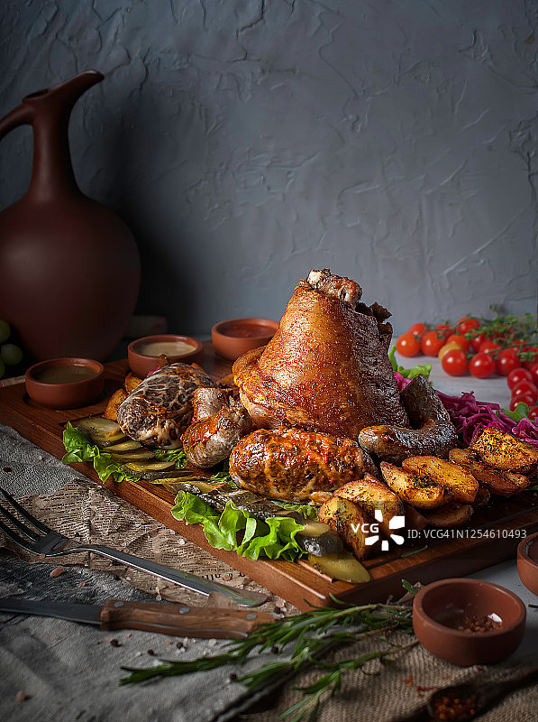 宴会美食摄影：大份美味肉类套餐，猪肘配自制香肠，灰色纹理背景图片素材