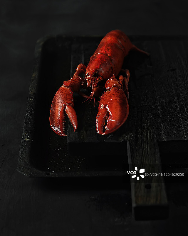 红龙虾美食摄影（深色木制厨房案板，黑色背景，极简主义风格，特写，侧视图）图片素材