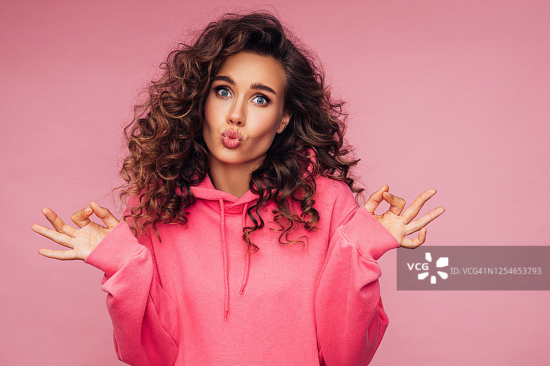 穿着粉色亮面帽衫的漂亮女孩，粉色背景图片素材