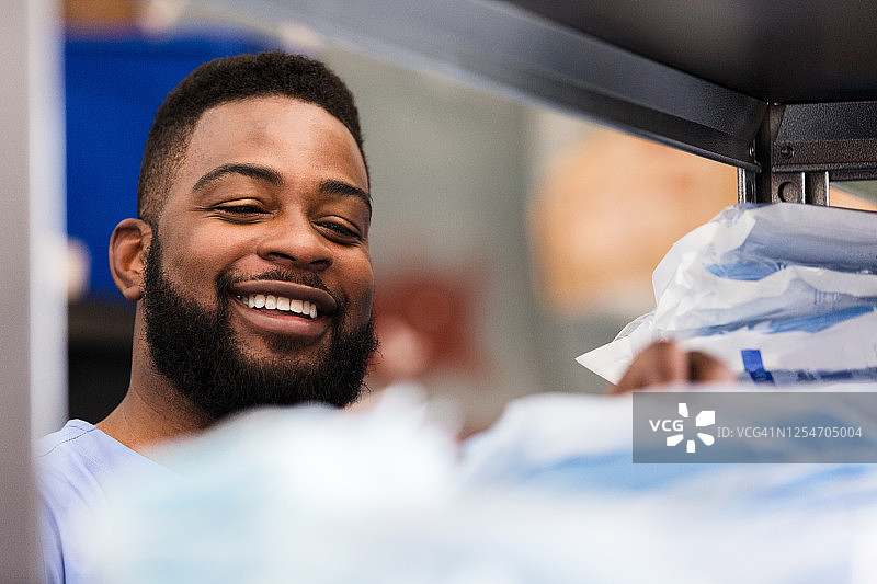 男医生在储藏室检查个人防护装备时微笑图片素材