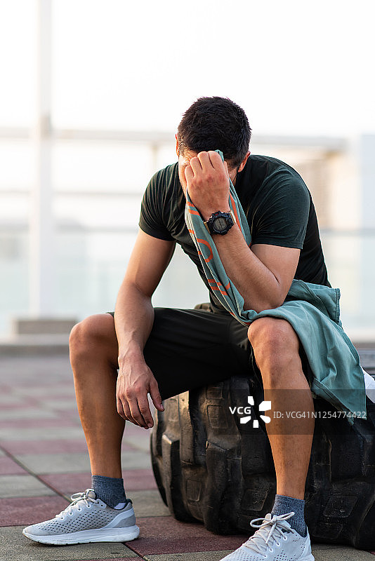 在户外锻炼后坐在拖拉机轮胎上的健壮男人图片素材
