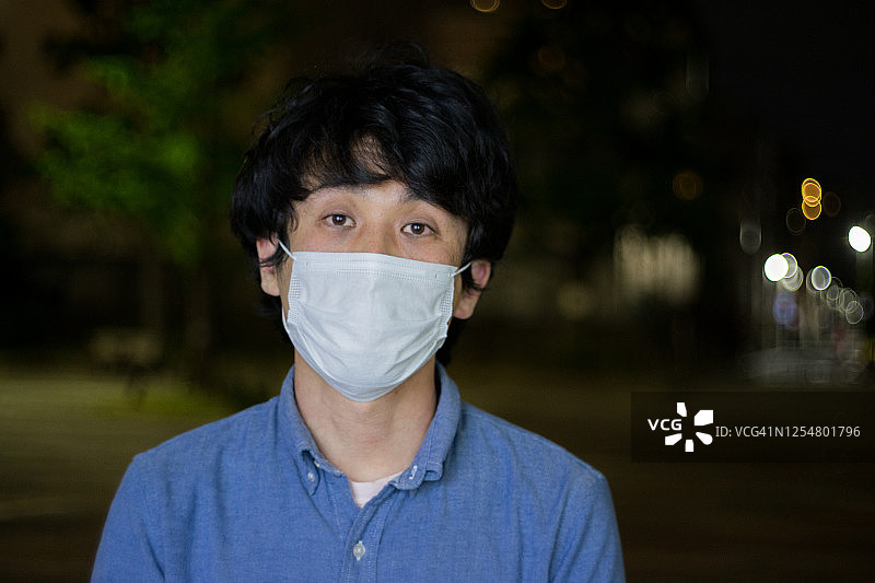 戴着外科口罩的男人和夜晚的城市图片素材