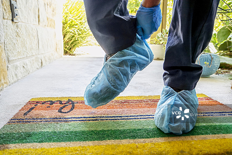 男子站在门垫上穿鞋套图片素材