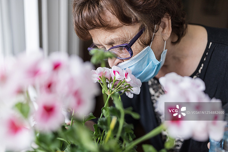 戴防护口罩嗅花的女人图片素材