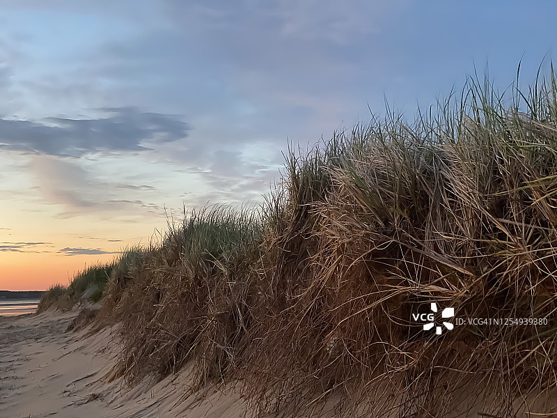 沙质悬崖之外科德角海滩上的壮丽日落图片素材