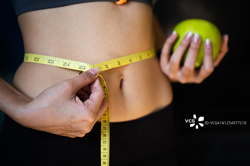 运动概念：女性用苹果锻炼，为了健康和减肥图片素材