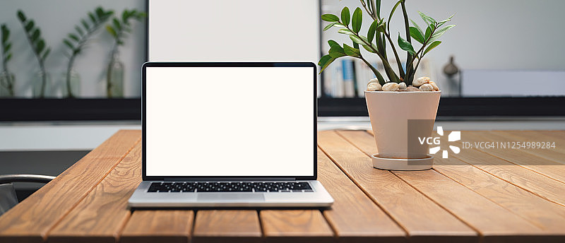 咖啡馆背景中桌子上带有空白白色屏幕的笔记本电脑。咖啡店模糊背景的桌子上带有空白屏幕的笔记本电脑。图片素材