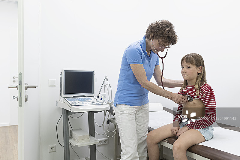 女医生用听诊器听小女孩的心跳图片素材