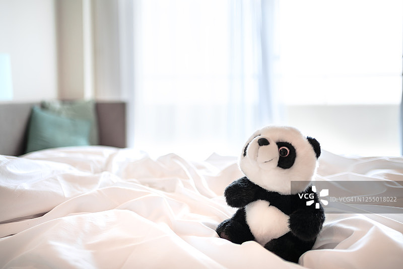 舒适的床和酒店晨曦中的熊猫玩具图片素材