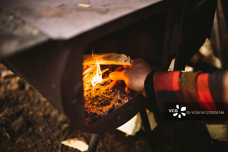 男人在旧式燃木炉中点火图片素材