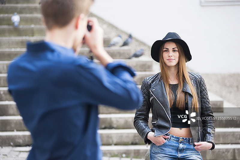 男子在城市台阶上用相机拍摄时尚女性图片素材