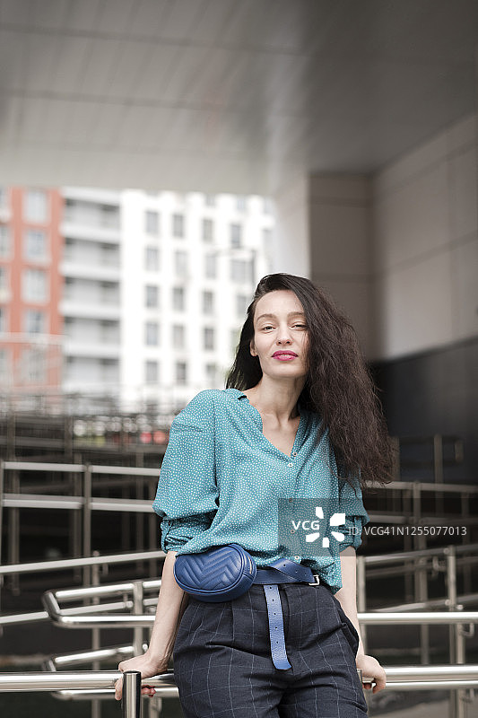 倚靠在城市栏杆上的长发美丽女人图片素材