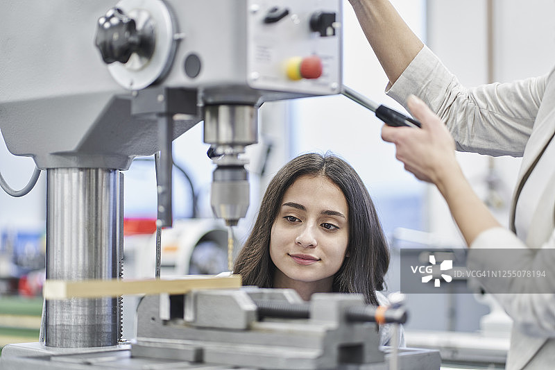 经理在金属行业培训女工，进行金属钻孔图片素材