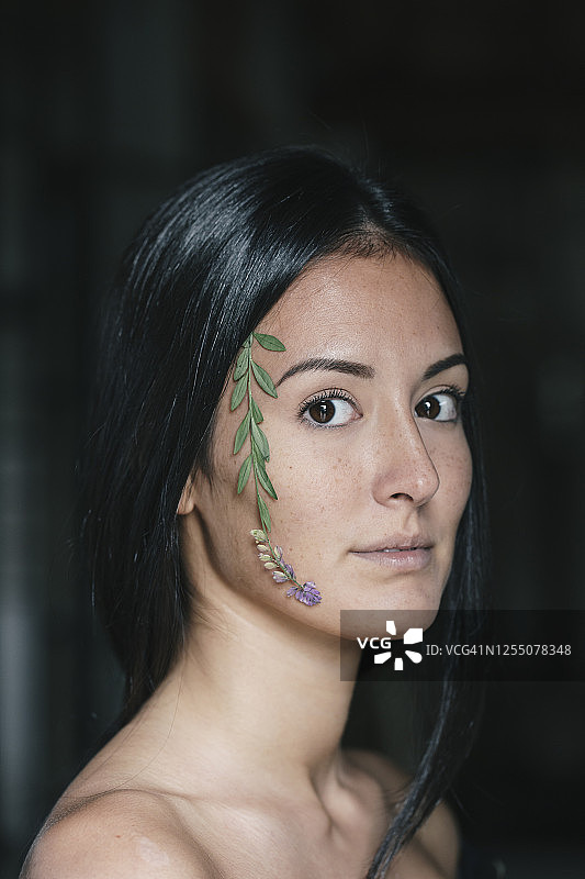 脸上贴着树叶的年轻漂亮女人图片素材