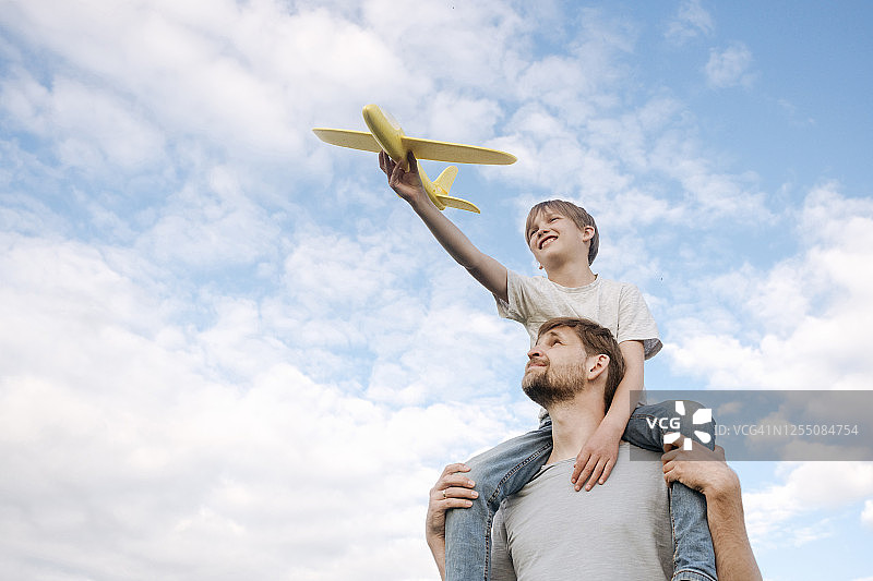 男人扛着儿子在肩上玩玩具飞机图片素材