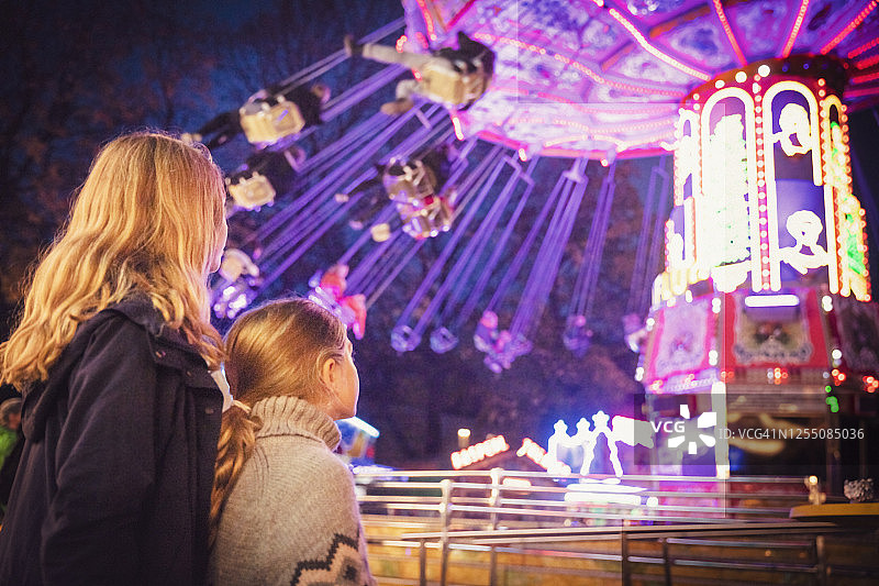 在德国慕尼黑，金发姐弟妹看着发光的链条弹簧游乐设施图片素材