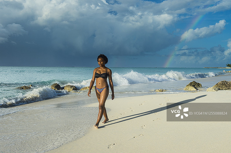 女子身穿比基尼在特克斯和凯科斯群岛普罗维登西亚莱斯岛格雷斯海湾海滩漫步图片素材