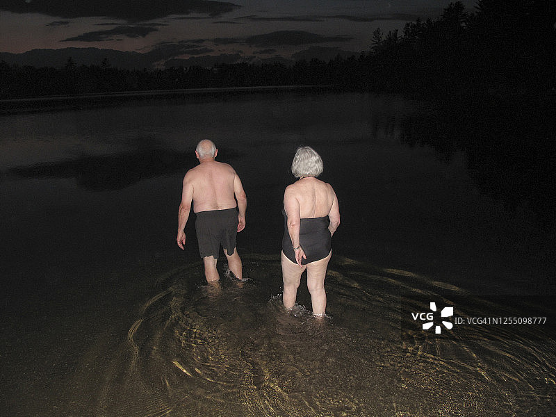 老年夫妇在小湖中涉水，准备夜间游泳图片素材