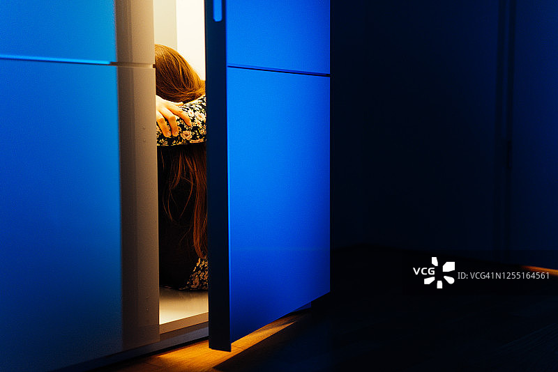 黑暗中坐在柜子里的悲伤女人图片素材