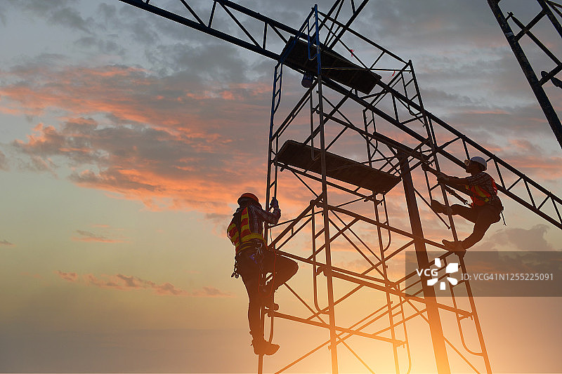 泰国两名建筑工人在脚手架上攀爬的剪影图片素材