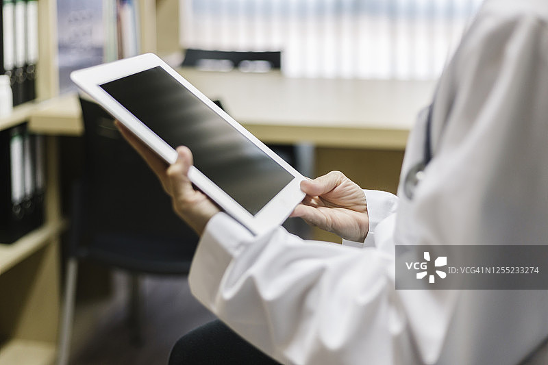 在诊所里拿着平板电脑的女医生的身体中部图片素材