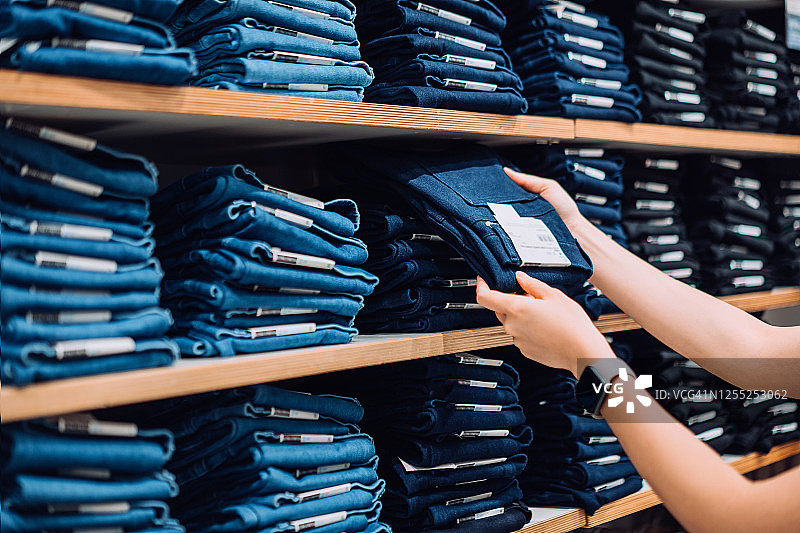 女人手在服装店货架上挑选裤子图片素材
