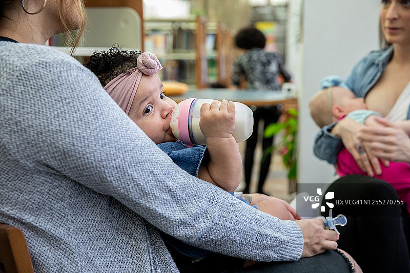 母亲支持小组会议：婴儿用奶瓶喝奶图片素材