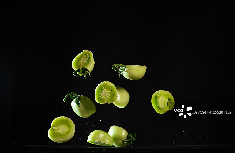 高速同步拍摄的半个绿色西红柿在空中飞舞图片素材