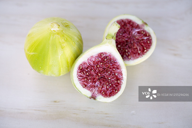 完整的无花果和切片的绿色无花果在木板上图片素材