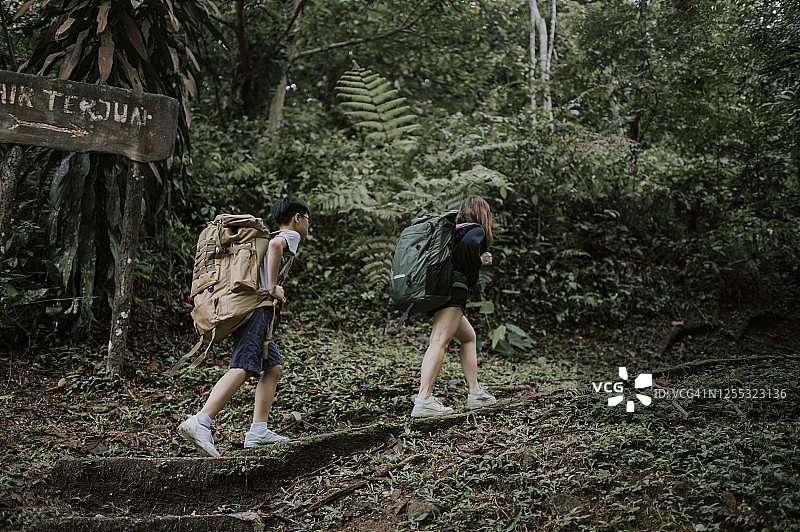 一位中国妇女带领儿子在早晨的丛林中徒步攀登图片素材