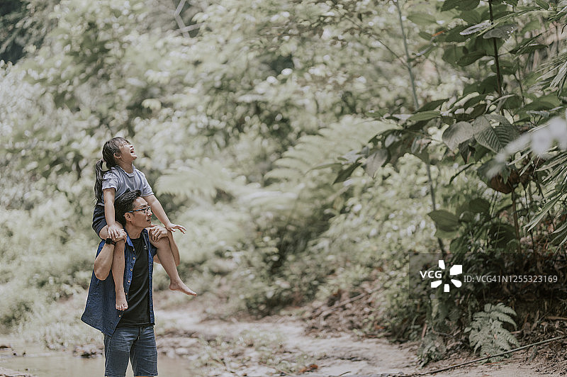 亚洲父亲在丛林中肩扛女儿享受亲子时光图片素材