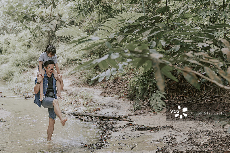 亚洲父亲在丛林中肩扛女儿享受亲子时光图片素材