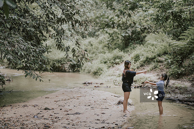 中国母亲和女儿在河边洗手的温馨时刻图片素材