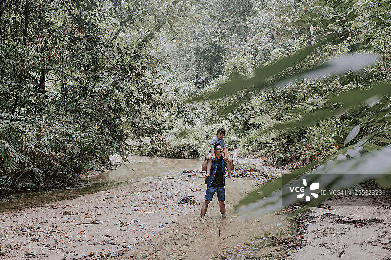 亚洲父亲在丛林中肩扛女儿享受亲子时光图片素材