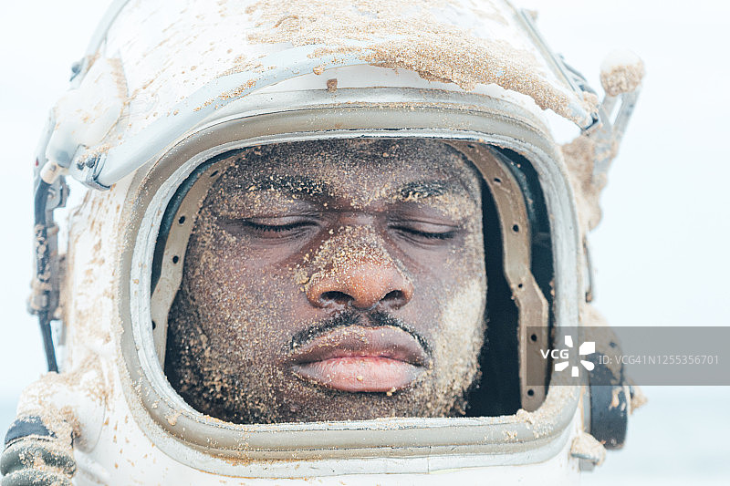 戴宇航员头盔，脸上沾着沙子的男人图片素材