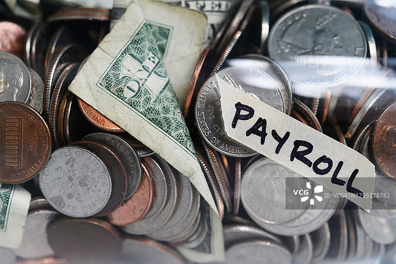 标有工资单的罐子里的硬币和纸币特写图片素材