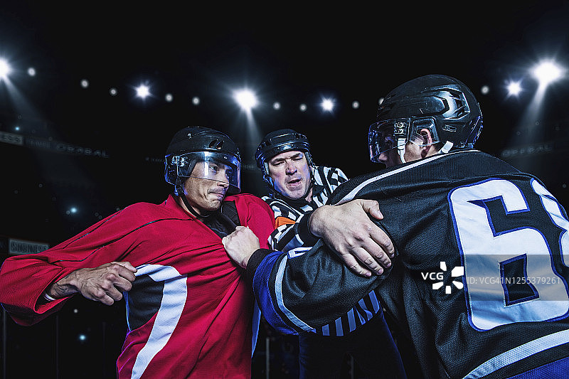 裁判分开打架的冰球运动员图片素材