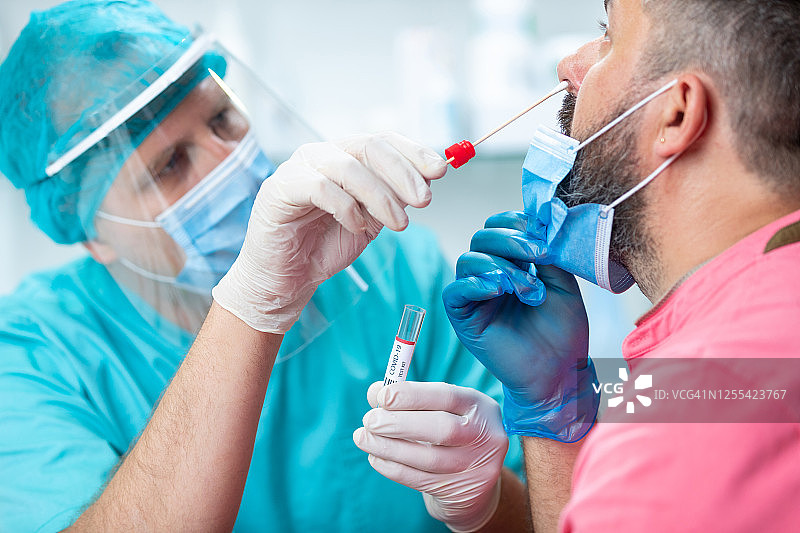 穿防护服的医生为病人做鼻拭子图片素材