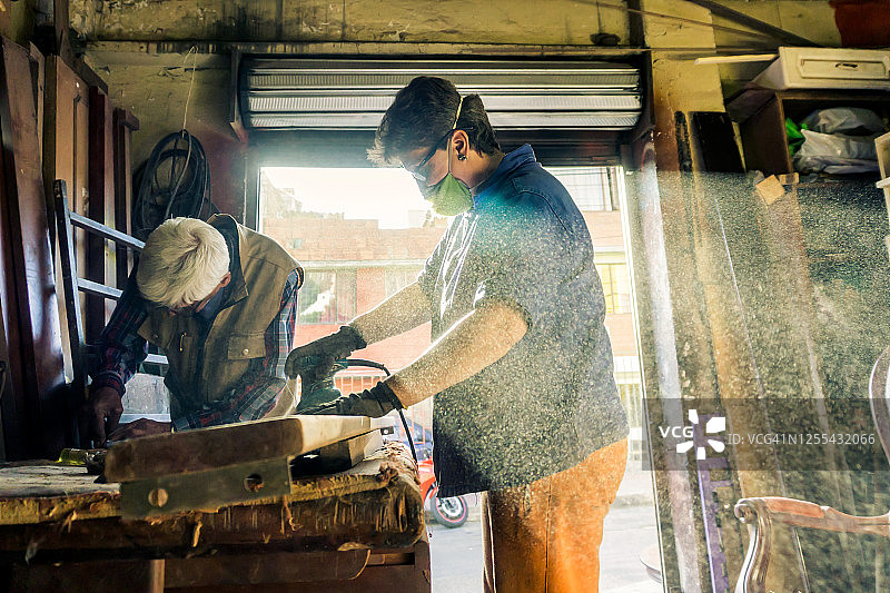 年长的女木匠打磨一块木头图片素材