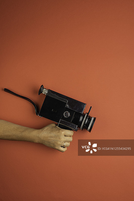 红色背景上手持复古8毫米相机的女人图片素材