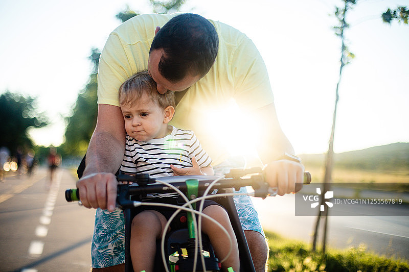 父亲骑自行车，儿子坐在座位上图片素材